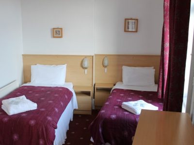 The Brooklyn Hotel twin room with two single beds that have red and white bedding